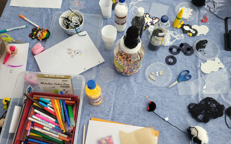 Basteltisch mit Material und malender Hand